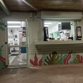 Yes Cafe - The image shows a restaurant window and door with a colorful mural of leaves and plants, and a glimpse of the kitchen inside. - Breakfast & Brunch Near Me - Miami, Florida