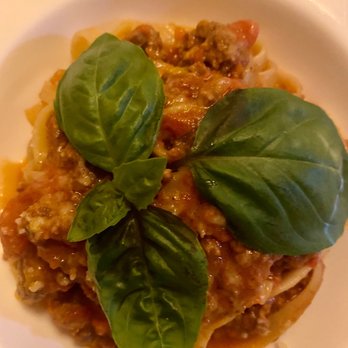 Sette - Tagliatelle Al Ragù - A serving of Tagliatelle Al Ragù with ground meat sauce, topped with fresh basil leaves, on a white plate. - Italian Near Me - Bernardsville, New Jersey