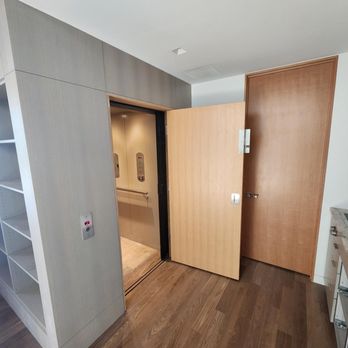 Arrow Lift - Modern home elevator with light wood interior and custom swing door, installed in contemporary residential space with built-in shelving. - Elevator Services Near Me - Appleton, Wisconsin