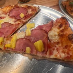 two slices of pizza with pineapples and ham