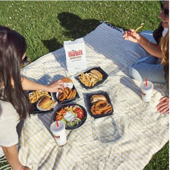 Habit Burger & Grill - wo women eating a meal on a picnic blanket - Salad Near Me - San Jacinto, California Habit Burger & Grill - wo women eating a meal on a picnic blanket - Salad Near Me - San Jacinto, California