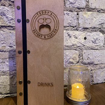 Teddy's Eatery & Parlor - a wooden menu book and candle - American Near Me - Fargo, North Dakota