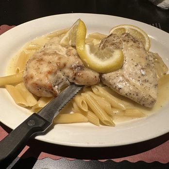 Lino's - Breast of Chicken Alla Francais with Mostaccioli (waitress asked if we wanted pasta under chicken and the sauce instead of red sauce) - A plate of pasta with chicken and fish fillets, garnished with lemon slices, served on an oval white dish. - Pizza Near Me - Rockford, Illinois