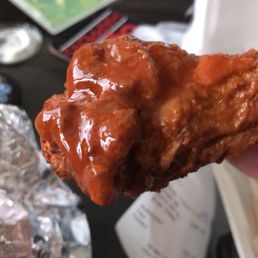a hand holding a piece of fried chicken