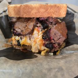 The Brisket Melt, 2 layers of brisket, layer of our special cheese mix, pickles, grilled onions, BBQ sauce between 2 pieces Texas Toast