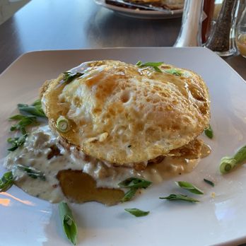 Redwater Kitchen - Two eggs over medium on the fried chicken beast also a crispy waffle covered with sausage gravy and chive garnish! - New American Near Me - Spearfish, South Dakota
