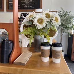 a coffee shop counter with coffee cups and flowers