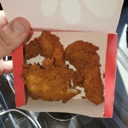 ows a hand holding a box of chicken nuggies