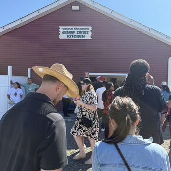 Barton Orchards - Visitors wait in line outside Barton Orchards' Granny Smith's Kitchen, with some wearing hats and sunglasses, under a clear blue sky. - Fruits & Veggies Near Me - Poughkeepsie, New York