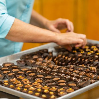 Wildflower Confections & Boutique - a woman placing chocolates on a tray - Bakeries Near Me - Darby, Montana Wildflower Confections & Boutique - a woman placing chocolates on a tray - Bakeries Near Me - Darby, Montana