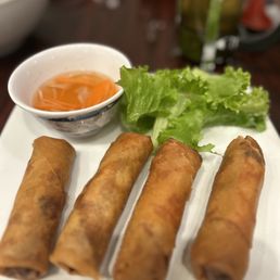a plate of fried spring rolls and a bowl of dipping sauce