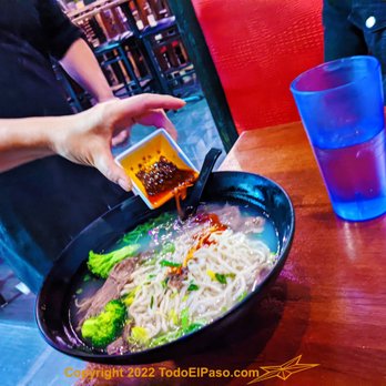 Grill Noodles Bar - a person dipping sauce over a bowl of noodles - Chinese Near Me - El Paso, Texas