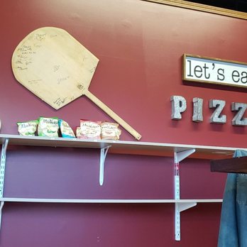 Nini's Pizzeria - a red wall with white shelves and a wooden paddle - Pizza Near Me - Greenfield, Wisconsin