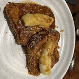 Crunchy French Toast - French toast with melted cheese on top, served with syrup and chopped nuts on a white plate, likely from a restaurant offering breakfast dishes.