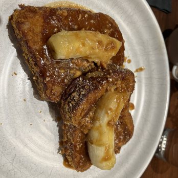 Kestra - Crunchy French Toast - French toast with melted cheese on top, served with syrup and chopped nuts on a white plate, likely from a restaurant offering breakfast dishes. - New American Near Me - Boston, Massachusetts