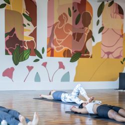 One Yoga Studio - Students take a yoga class in the studio. The mural by Moon Juice Murals and Silent Fox Studio is in the background.