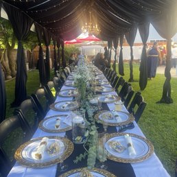 Tent with draping, lights & chandelier. Tables with linen and black chairs. Tent with draping, lights & chandelier. Tables with linen and black chairs.