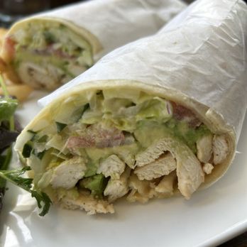 Ivy Cafe - Grilled chicken wrap with fries and salad - A chicken wrap filled with lettuce, salad, and chicken pieces, wrapped in white paper, served on a white plate with a side salad. - Coffee & Tea Near Me - Brooklyn, New York