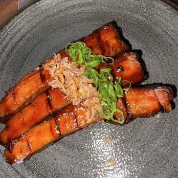 Shiso - Ribs - Barbecue ribs glazed with sauce, topped with chopped green onions and crispy shallots, served on a dark ceramic plate. - Cocktail Bars Near Me - Miami, Florida