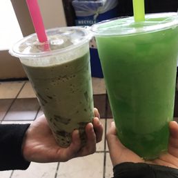 a person holding a green drink and a drink in a plastic cup