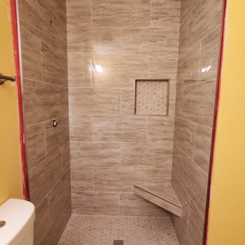 Improving Construction - a walk in shower with a bench - General Contractors Near Me