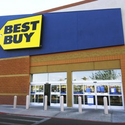 Exterior view of a Best Buy store with a prominent yellow and black sign, glass doors, and a blue banner on the side.