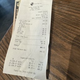 A printed receipt from Another Broken Egg Cafe in El Paso, TX, showing food and beverage items, prices, and total amount, on a wooden table.