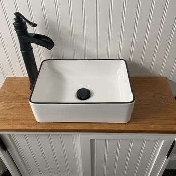 Victor's Finish Work - Custom vanity - Rectangular white vessel sink with a black drain, installed on a wooden countertop, accompanied by a black faucet, against a white beadboard wall. - Refinishing Services Near Me