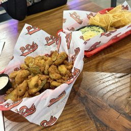 Fried pickle and artichoke dip. Yum - Fried pickles and artichoke dip are served on a wooden table at P-Dubs Brew Pub, a venue with a diverse menu and entertainment options.
