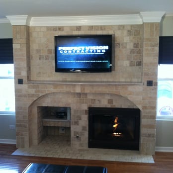 Perfect Vision Contracting - a television mounted on a brick fireplace - General Contractors Near Me Perfect Vision Contracting - a television mounted on a brick fireplace - General Contractors Near Me