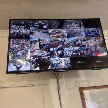 Ibarra's Security - A wall-mounted security monitor shows multiple camera feeds of parking lots and interior spaces, with some feeds labeled 'No Camera' and a timestamp. - Security Systems Near Me