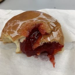 a half eaten donut with jam on it
