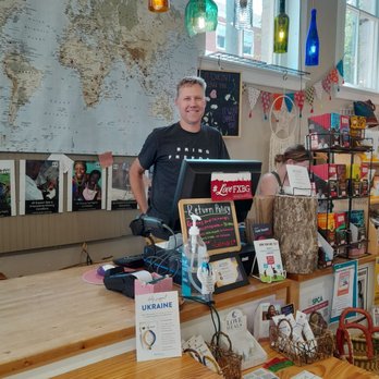 Latitudes Fair Trade Store - One of the owners and world map and register. - Accessories Near Me - Fredericksburg, Virginia