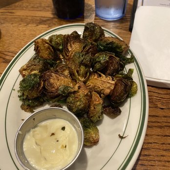 Cover Two - Fried Brussels sprouts with garlic aioli - Fried Brussels sprouts served on a white oval plate with a small cup of dipping sauce, accompanied by drinks and a napkin on a restaurant table. - American Near Me - Newtown, Connecticut