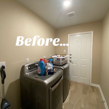 Creating Sacred Spaces - A laundry room features a washing machine and dryer with laundry supplies on top, and a laundry basket. The room has beige walls and a wooden floor. - Interior Design Near Me - Austin, Texas