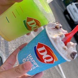 a hand holding two cups of ice cream