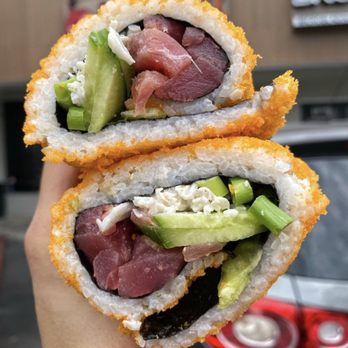 Pokitomik - a hand holding a piece of sushi - Poke Near Me - Montebello, California