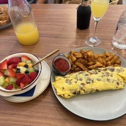 Cheese Omelette with mushroom and sausage. Side of breakfast potatoes and fruit.