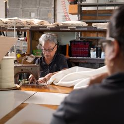 An Oklahoma Mattress Company craftswoman sews a cotton mattress cover.