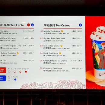 Fortune Tea - Menu on wall - The image features a digital menu board at Fortune Tea in Toronto, displaying a selection of tea latte and tea crème beverages. The menu includes items such as Black Tea Latte, Big Red Robe Tea Latte, and Four Season Oolong Tea Latte, with prices ranging from $6.1 to $6.9. Tea crème options include Matcha, Lychee, and Chestnut Mochi, priced between $6.5 and $7.5. Customization options for sugar and ice levels are also shown, with symbols indicating different levels. To the right of the menu, there is a colorful cup with a decorative sleeve, topped with whipped cream and red toppings. - Bubble Tea Near Me - Toronto, Ontario