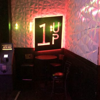 1 Up - a table and chairs in a dimly lit room - Bars Near Me - Reno, Nevada