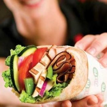 Pita Pit - a woman holding a pita sandwich - Fast Food Near Me - Dillon, Montana