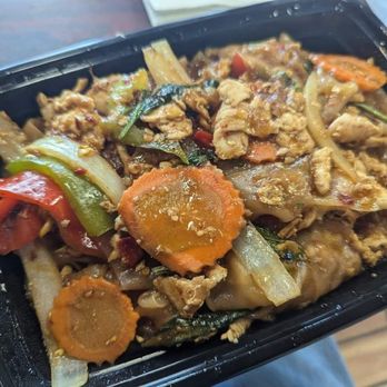 Thai Cafe 88 - Singapore Noodles - A black plastic takeout container holds stir-fried noodles with vegetables like carrots, bell peppers, and onions, along with pieces of chicken. - Thai Near Me - Garnerville, New York
