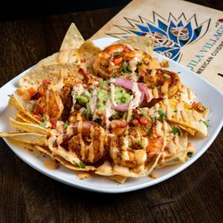 Tequila Village Mexican Cuisine Monument - A plate of Mexican cuisine sits beside a menu on a wooden table at Tequila Village in Monument.