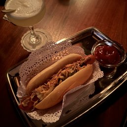 a hot dog and a cocktail on a tray