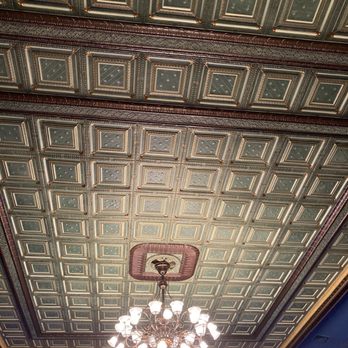 Stoughton Opera House - Beautiful ceiling tiles! - Ceiling features decorative square tiles with intricate patterns and a central chandelier with multiple lights. - Performing Arts Near Me - Stoughton, Wisconsin