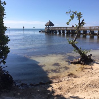 Ocean Pointe Suites at Key Largo - Beach view with a nice pier that has a tiki hut and seats at the end - Hotels Near Me - Key Largo, Florida
