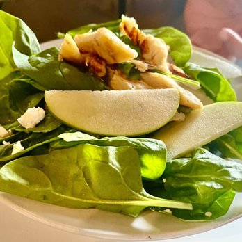 Teavolve - Chicken & Apple Salad - A fresh salad featuring spinach leaves, sliced pears, grilled chicken pieces, and crumbled cheese served on a white plate. - Coffee & Tea Near Me - Baltimore, Maryland