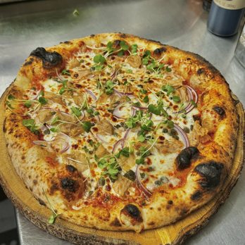 Mulata Artisan Pizzeria - a pizza on a table - Pizza Near Me - Orlando, Florida Mulata Artisan Pizzeria - a pizza on a table - Pizza Near Me - Orlando, Florida