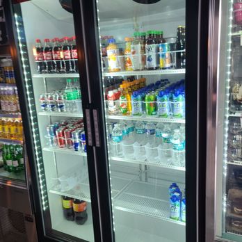 Bean and Blend Cafe - Drinks - A glass-door refrigerated beverage cooler stocked with bottled water, juice, and soda, located in a convenience store setting. - Coffee & Tea Near Me - Tabernacle, New Jersey